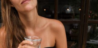 Młoda dziewczyna, z długimi blond włosami, w czarnej koszulce bez ramiączek pije wodę. To przykład tego, jak mogą wyglądać zdrowe rytuały.
