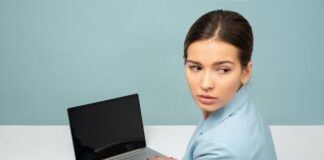 Młoda kobieta z upiętymi włosami siedzi przy biurku przed komputerem. Na jej twarzy maluje się stres.